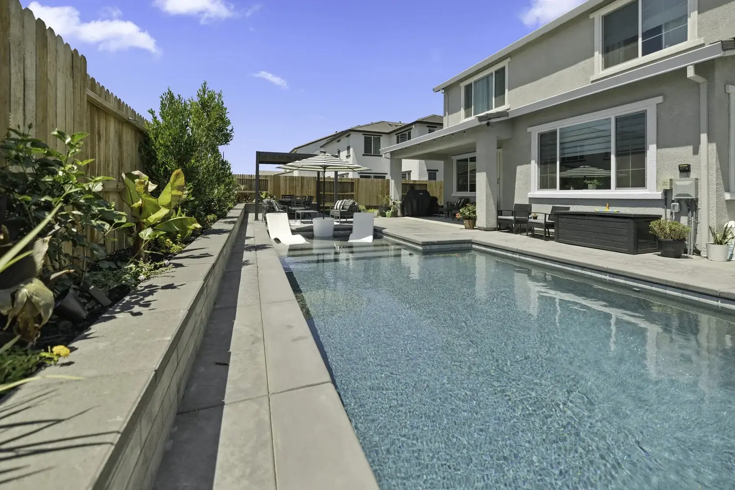 Backyard lap pool alongside a planted retaining wall