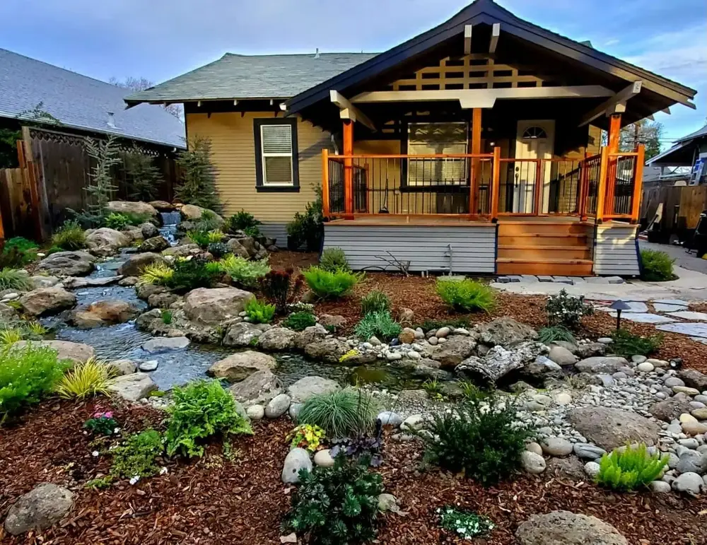 Pondless stream running through a front yard past a craftsman porch