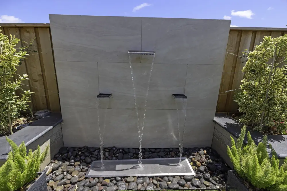 Modern architectural water wall with twin sheet spillways over a pebble basin