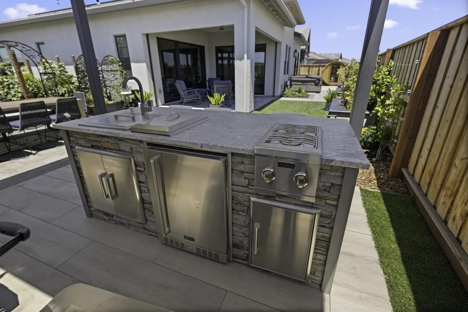 Stone-faced outdoor kitchen island with stainless appliances