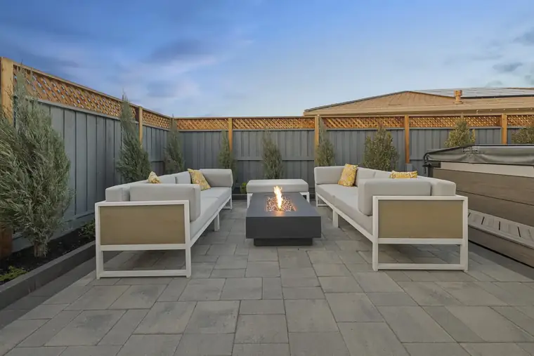 Linear fire table between white sofas on a paver terrace