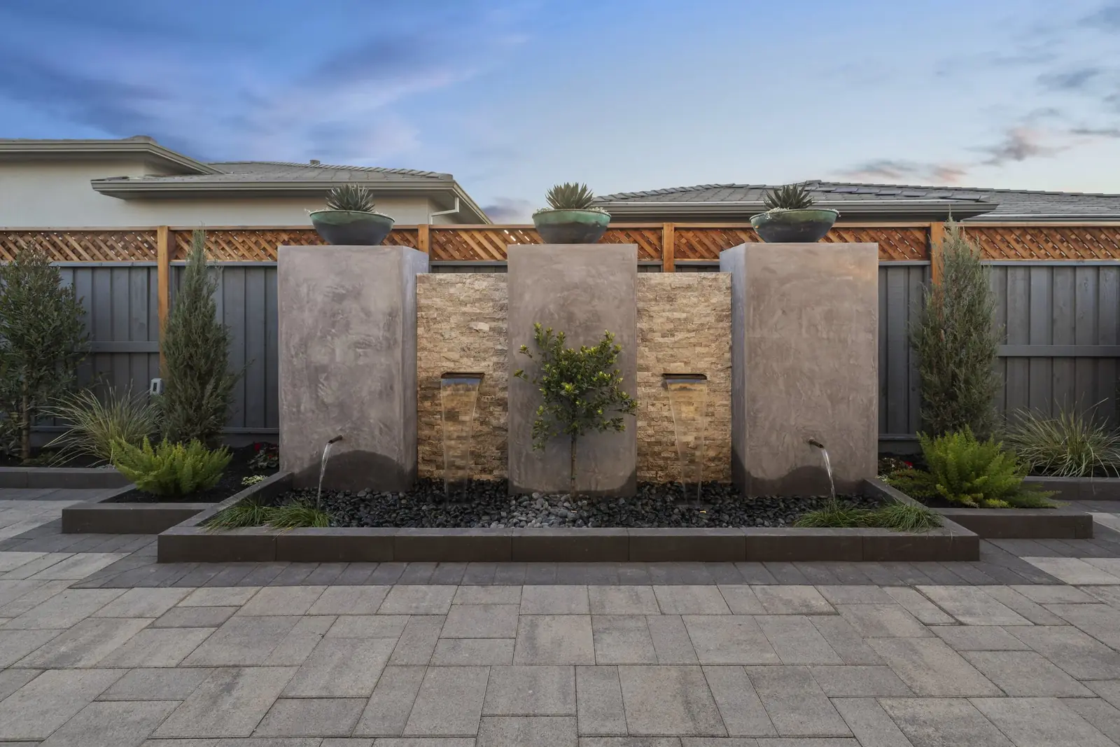 Paver walkway passing a row of stucco water-feature panels