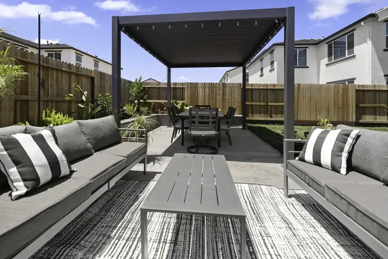 Modern pergola over an outdoor sofa styled with striped pillows
