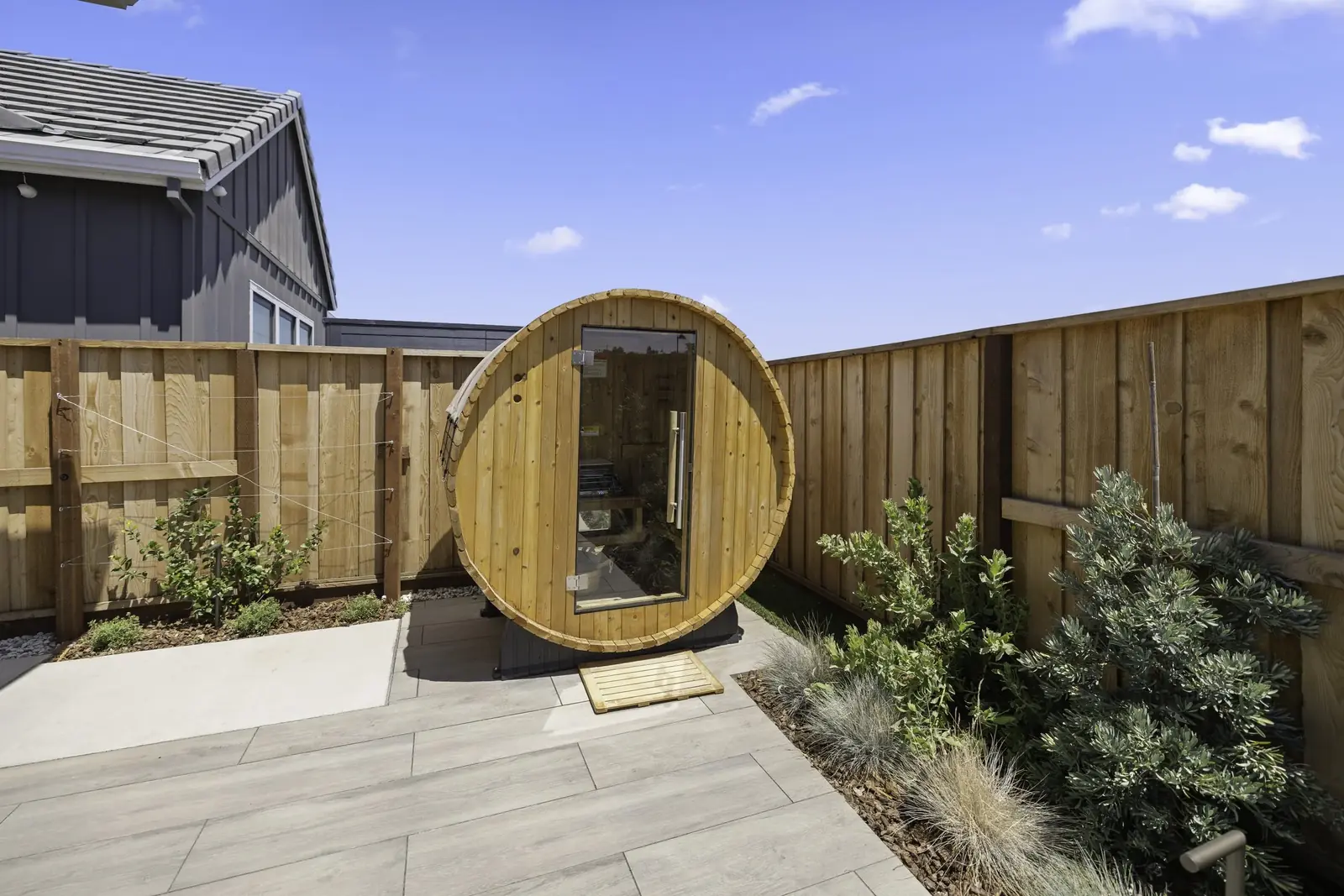 Barrel sauna and hot tub installed in a compact backyard